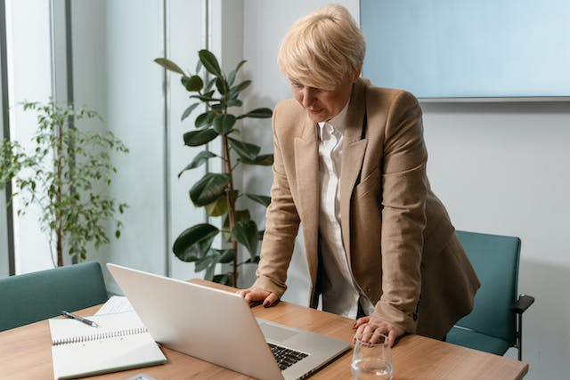 a property manager in a light brown jacket standing at their desk looking at a computer